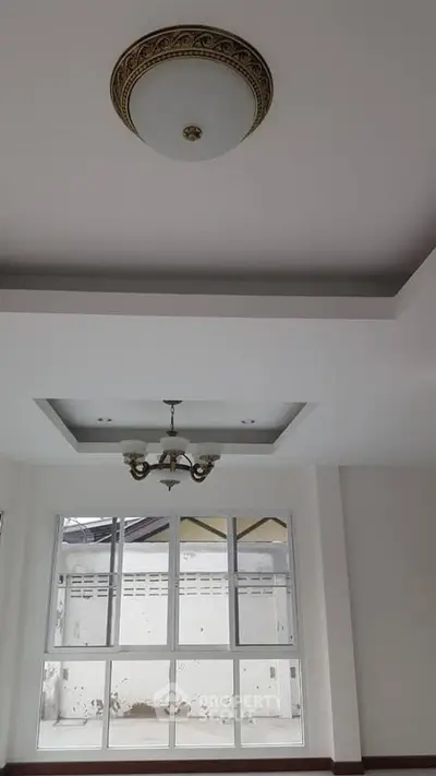Elegant ceiling design with chandelier in a bright room with large window