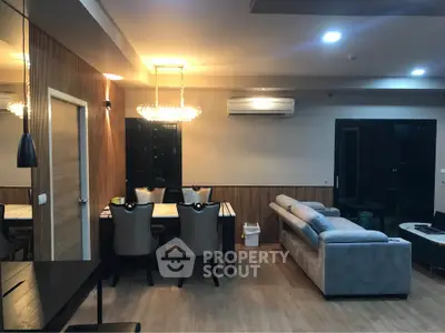 Modern living room with elegant dining area and cozy seating, featuring stylish lighting and wooden accents.