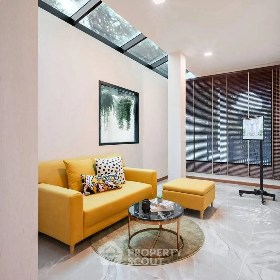 Modern living room with yellow sofa and skylight, featuring stylish decor and natural light.