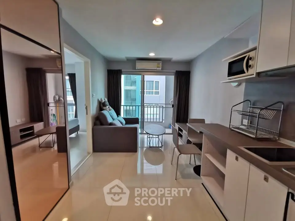 Modern living room with open kitchen and balcony view in stylish apartment.