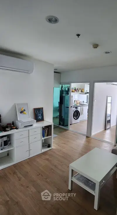 Modern living room with wooden flooring and open view to kitchen area