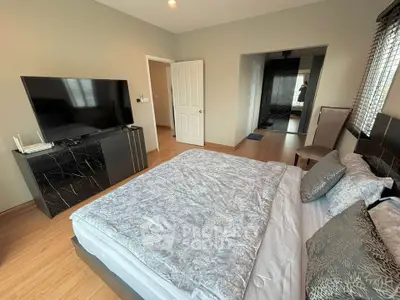 Spacious modern bedroom with stylish decor and large TV