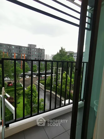 Charming balcony view overlooking lush greenery and modern apartment complex.