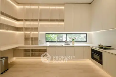Modern kitchen with sleek cabinetry and large window, featuring integrated appliances and ambient lighting.