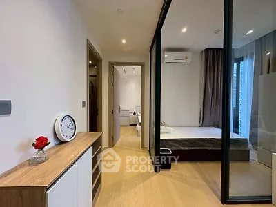 Modern bedroom with glass partition and wooden flooring, featuring a sleek design and natural light.