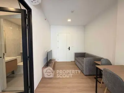 Modern living room with sleek furniture and wooden flooring, adjacent to a stylish bathroom.