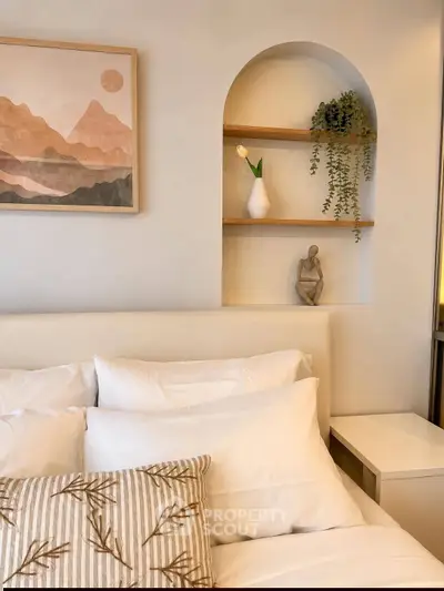 Cozy bedroom with elegant decor, featuring a plush bed, stylish artwork, and decorative shelves.