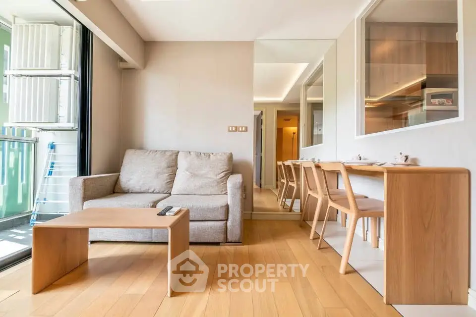 Modern living room with cozy sofa and dining area, featuring wooden flooring and natural light.