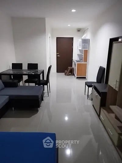 Modern apartment interior with sleek furniture and open layout, featuring a cozy dining area and compact kitchen.