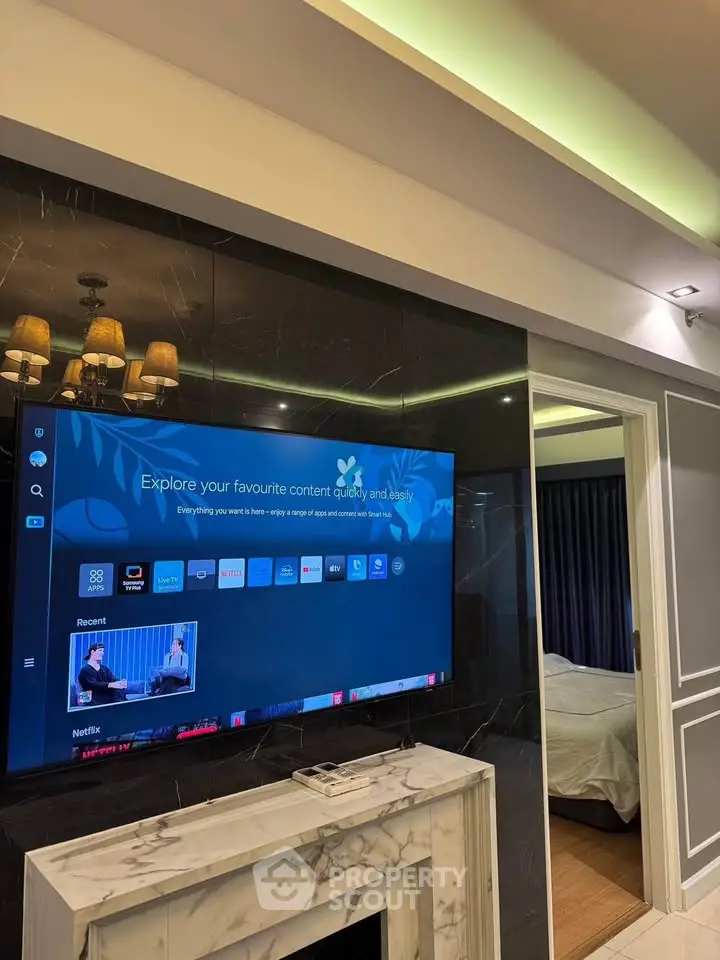 Modern living room with wall-mounted TV and elegant decor leading to a cozy bedroom.