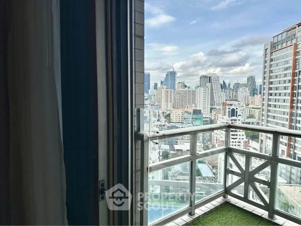 Stunning cityscape view from a modern high-rise balcony with glass railing.