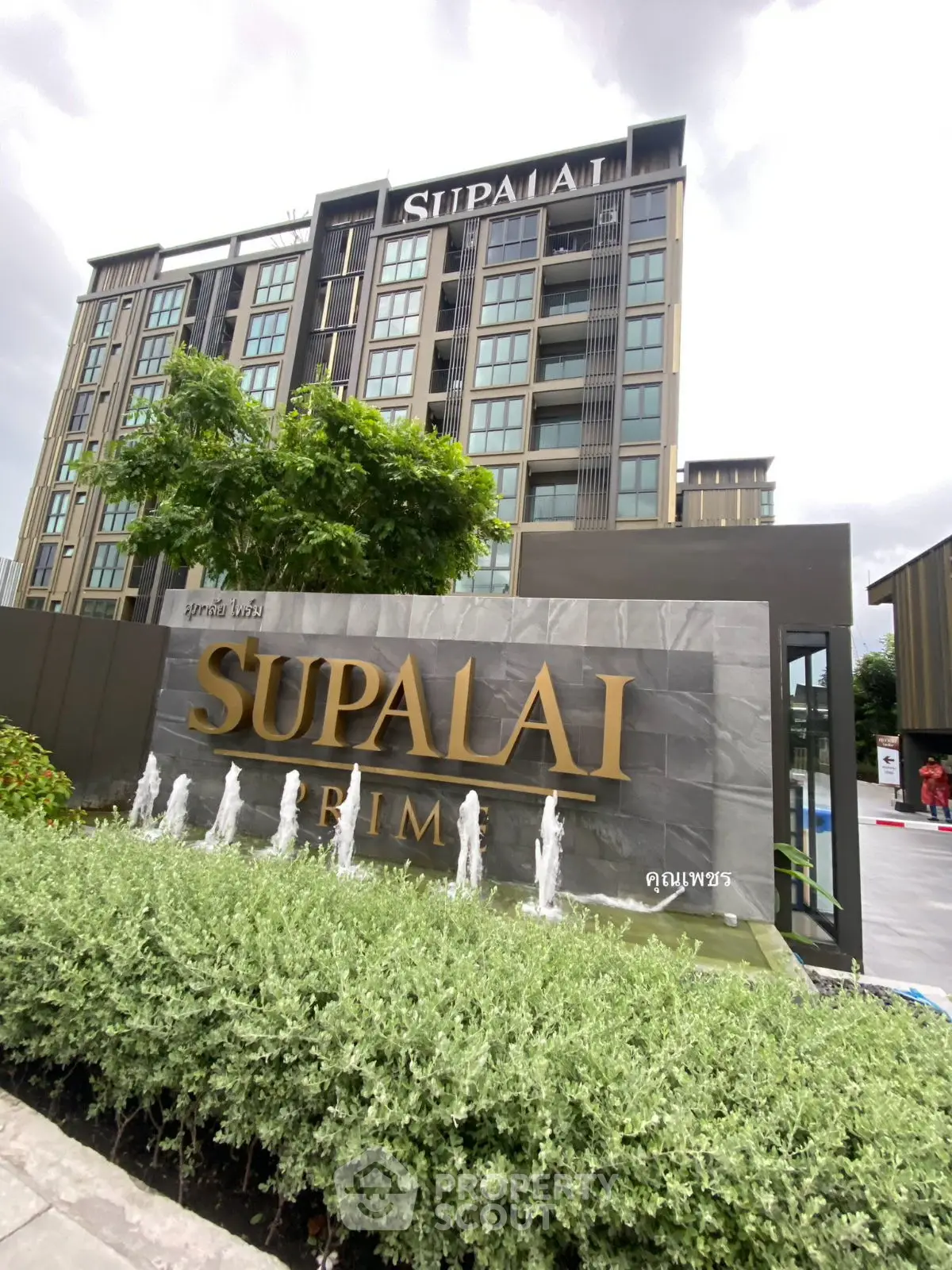 Modern condominium building with lush greenery and elegant signage