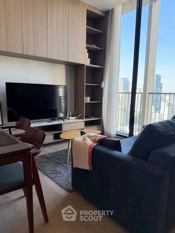 Modern living room with city view, stylish furniture, and large TV in a high-rise apartment.