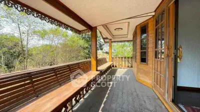Charming wooden balcony with intricate railing and lush greenery view.