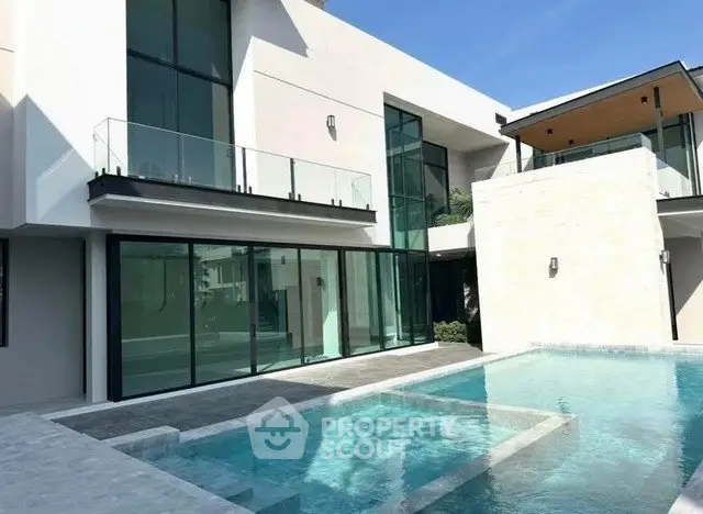 Luxurious modern home with sleek glass facade and stunning private pool.