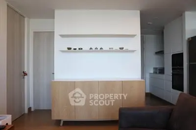 Modern minimalist living room with sleek cabinetry and open kitchen layout.