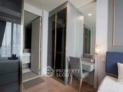 Modern bedroom with sleek design, featuring a mirrored wardrobe and cozy workspace.