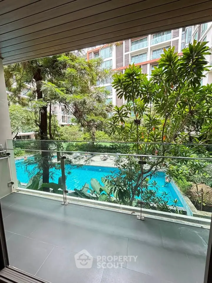 Luxurious balcony view overlooking a serene pool and lush greenery in a modern residential complex.