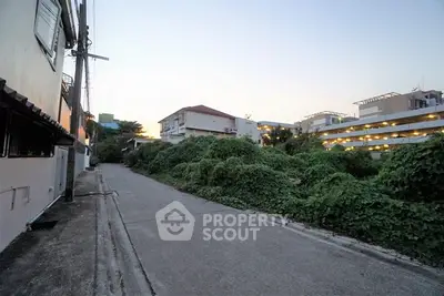 Charming residential street view with lush greenery and urban surroundings at dusk.
