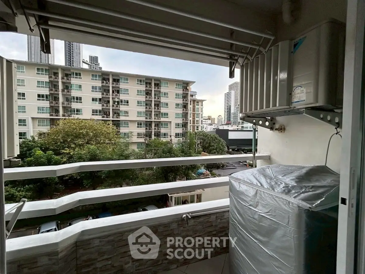 Charming balcony with city view and air conditioning unit in urban apartment.