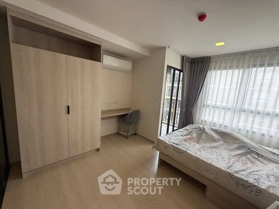 Spacious bedroom with large windows and modern furnishings in a stylish apartment.
