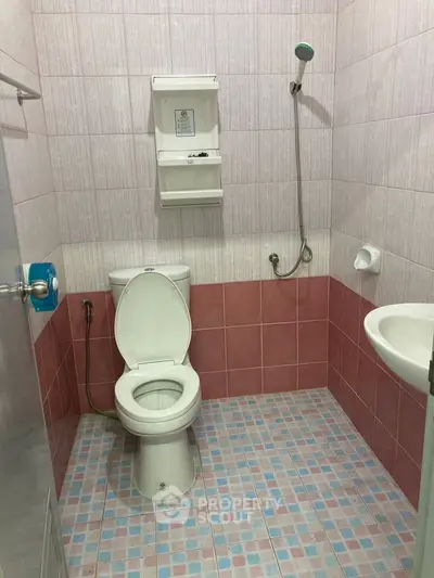 Compact bathroom with pink tiles and basic fixtures, ideal for small spaces.