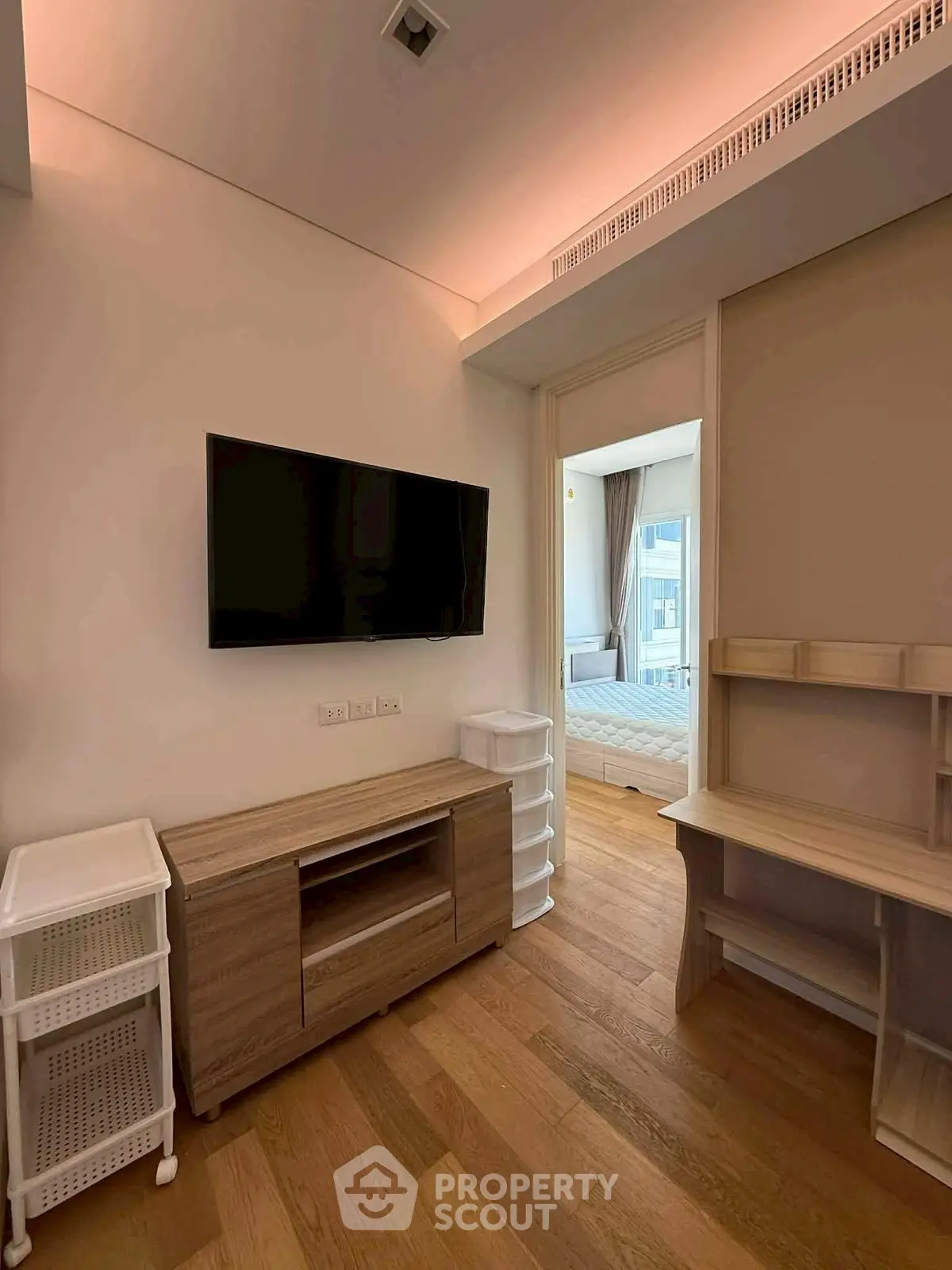 Modern apartment interior with wooden flooring and wall-mounted TV in a cozy living space.