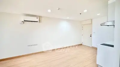 Spacious minimalist living area with air conditioning and modern kitchen corner.