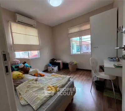 Cozy bedroom with wooden flooring and natural light, perfect for a comfortable living space.
