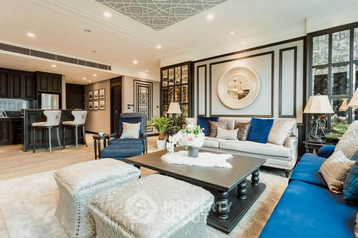 Luxurious living room with elegant decor and open kitchen layout, featuring plush seating and stylish lighting.
