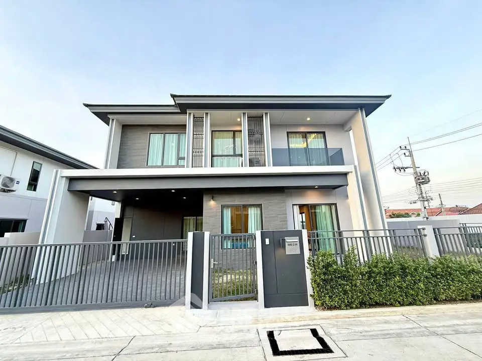Modern two-story house with sleek design and spacious driveway in suburban neighborhood.