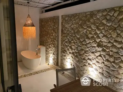 Luxurious outdoor bathtub with stone wall and ambient lighting