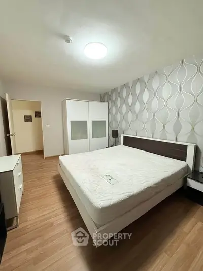 Spacious modern bedroom with stylish wallpaper and wooden flooring