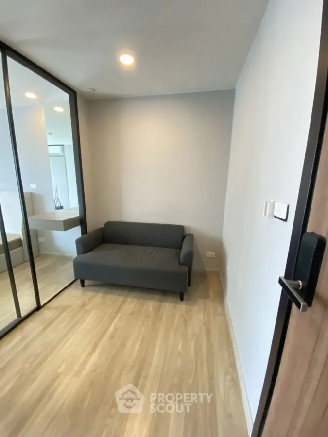 Modern small living room with sleek sofa and mirrored wardrobe
