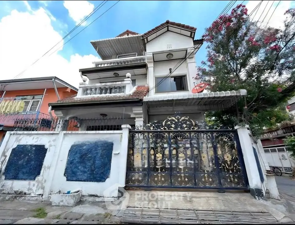 Charming multi-story house with ornate gate and balcony in a vibrant neighborhood.