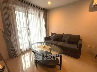 Cozy living room with modern sofa and glass coffee table, featuring floor-to-ceiling windows and elegant curtains.