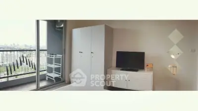 Modern bedroom with balcony view, featuring sleek furniture and cityscape backdrop.