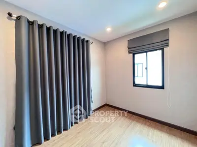 Spacious empty room with wooden flooring and large window