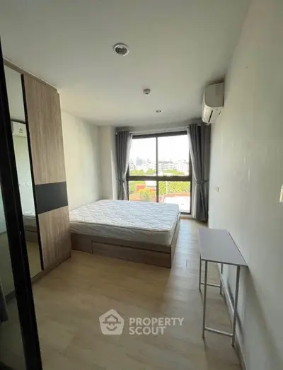 Modern bedroom with large window and minimalist furniture in a bright apartment.