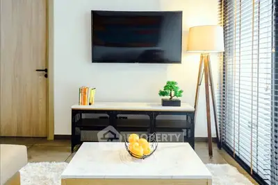 Modern living room with stylish decor, flat-screen TV, and natural light.