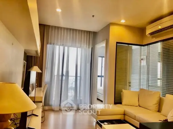 Modern living room with cozy sofa and natural light through large windows.