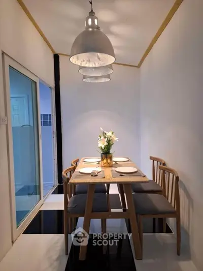 Modern dining area with stylish wooden table and chairs, elegant lighting, and minimalist decor.