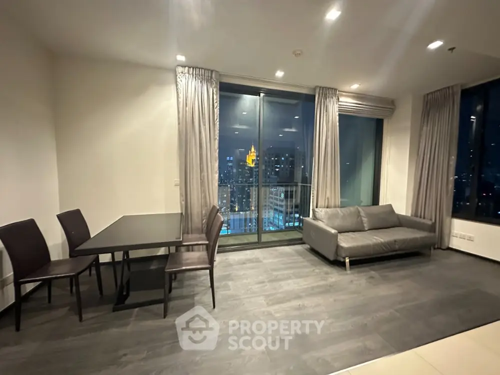 Spacious high-rise living room with floor-to-ceiling windows offering a stunning cityscape view, modern furnishings, and sleek flooring.