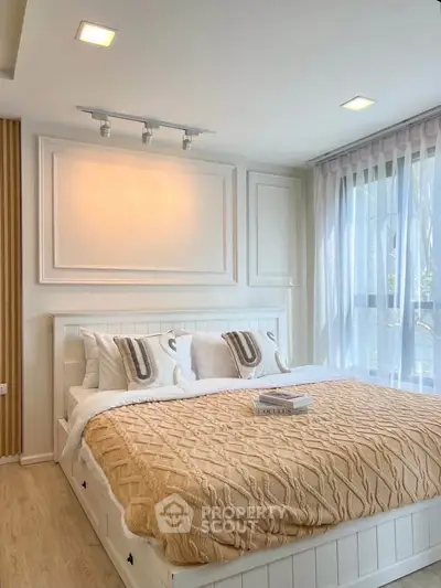Elegant bedroom with cozy bedding and large window offering natural light