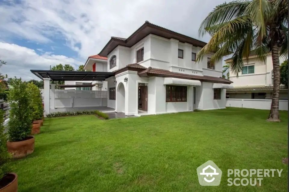 Charming two-story house with lush green lawn and palm tree, perfect for family living.