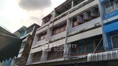 Charming multi-story building with unique window design and rustic exterior in urban setting.
