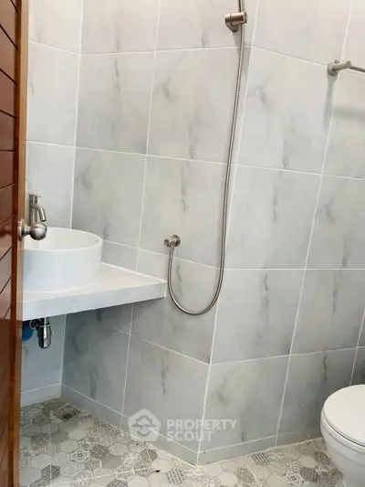Modern bathroom with sleek fixtures and minimalist design, featuring a wall-mounted sink and shower.