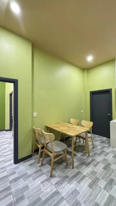 Modern dining area with green walls and wooden furniture in a cozy home setting.