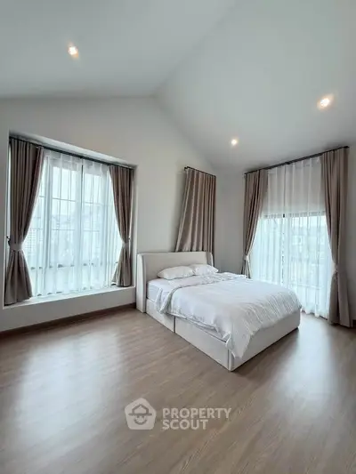 Spacious bedroom with large windows and elegant curtains in modern home