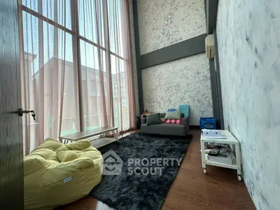 Spacious living room with high ceilings and large windows, featuring cozy seating and modern decor.